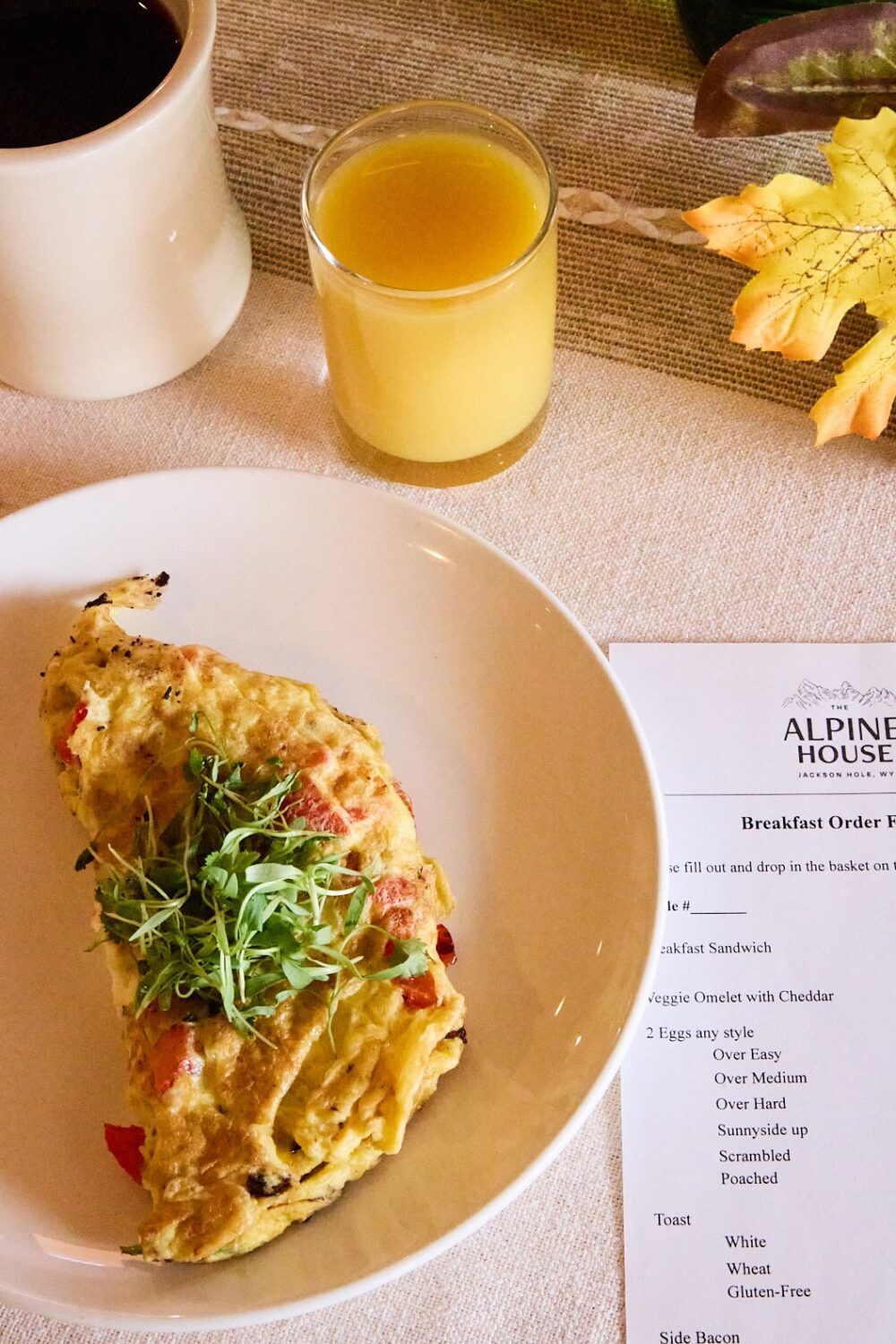 An omelette with a green garnish and a glass of orange juice.