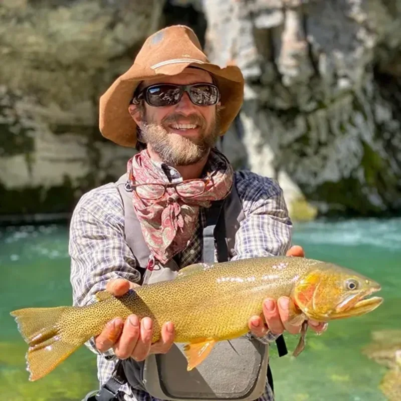 A man holding a fish in a stream.