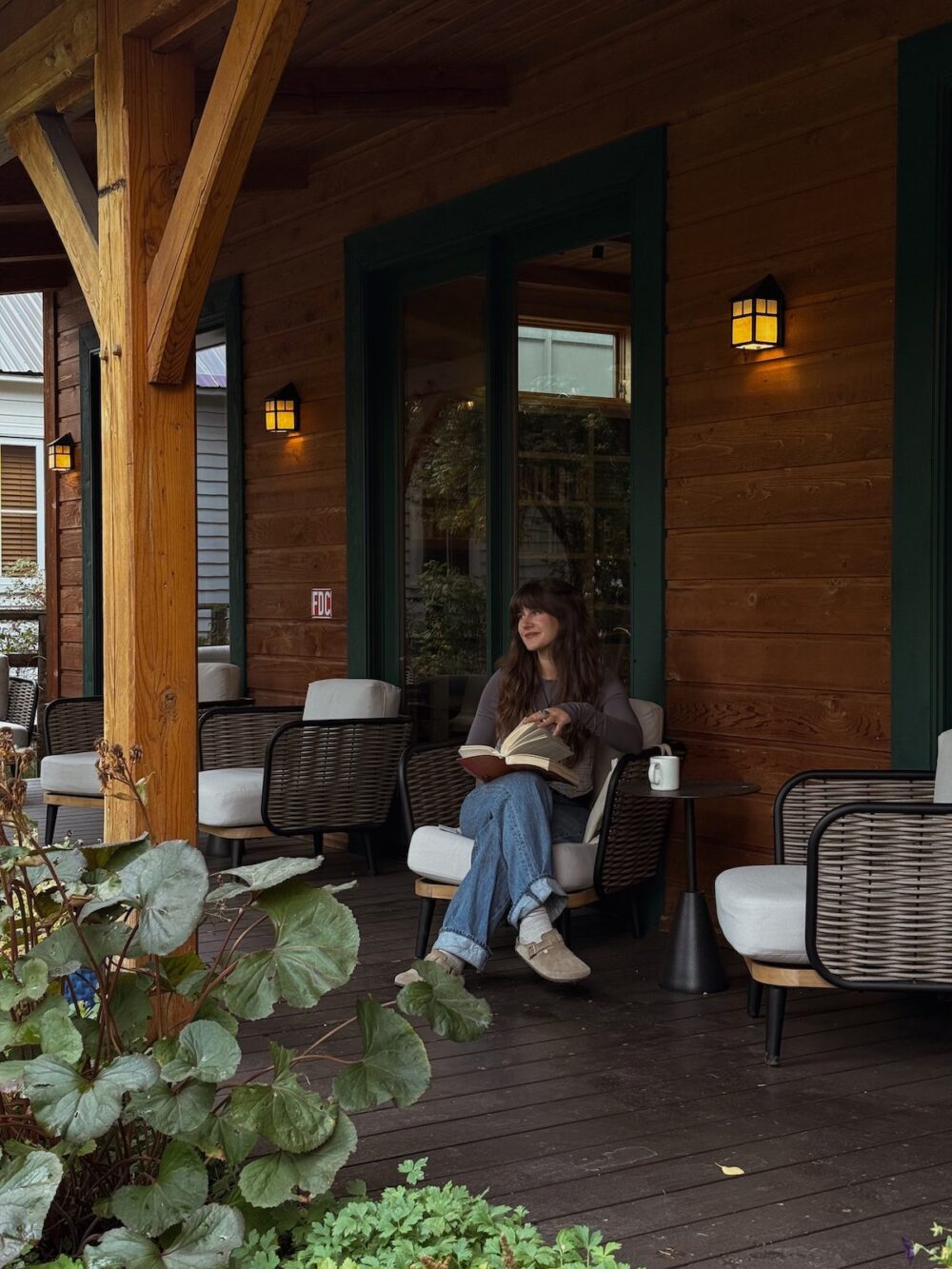 A woman reading on the porch at The Alpine House.